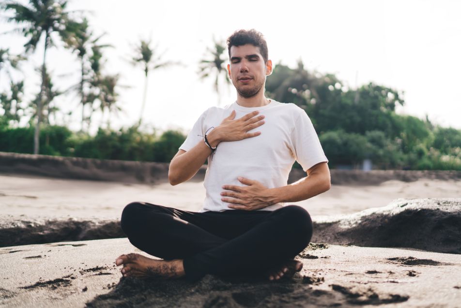 Man on beach practicing breathing, meditating