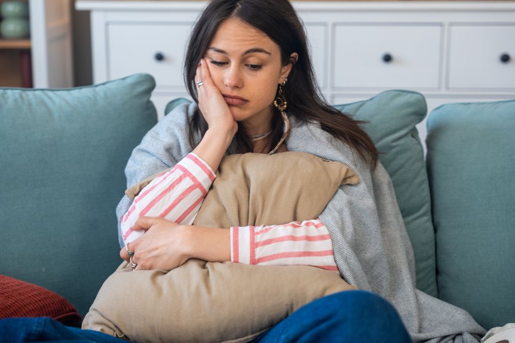 Woman looking forlorn with pillow and blanket