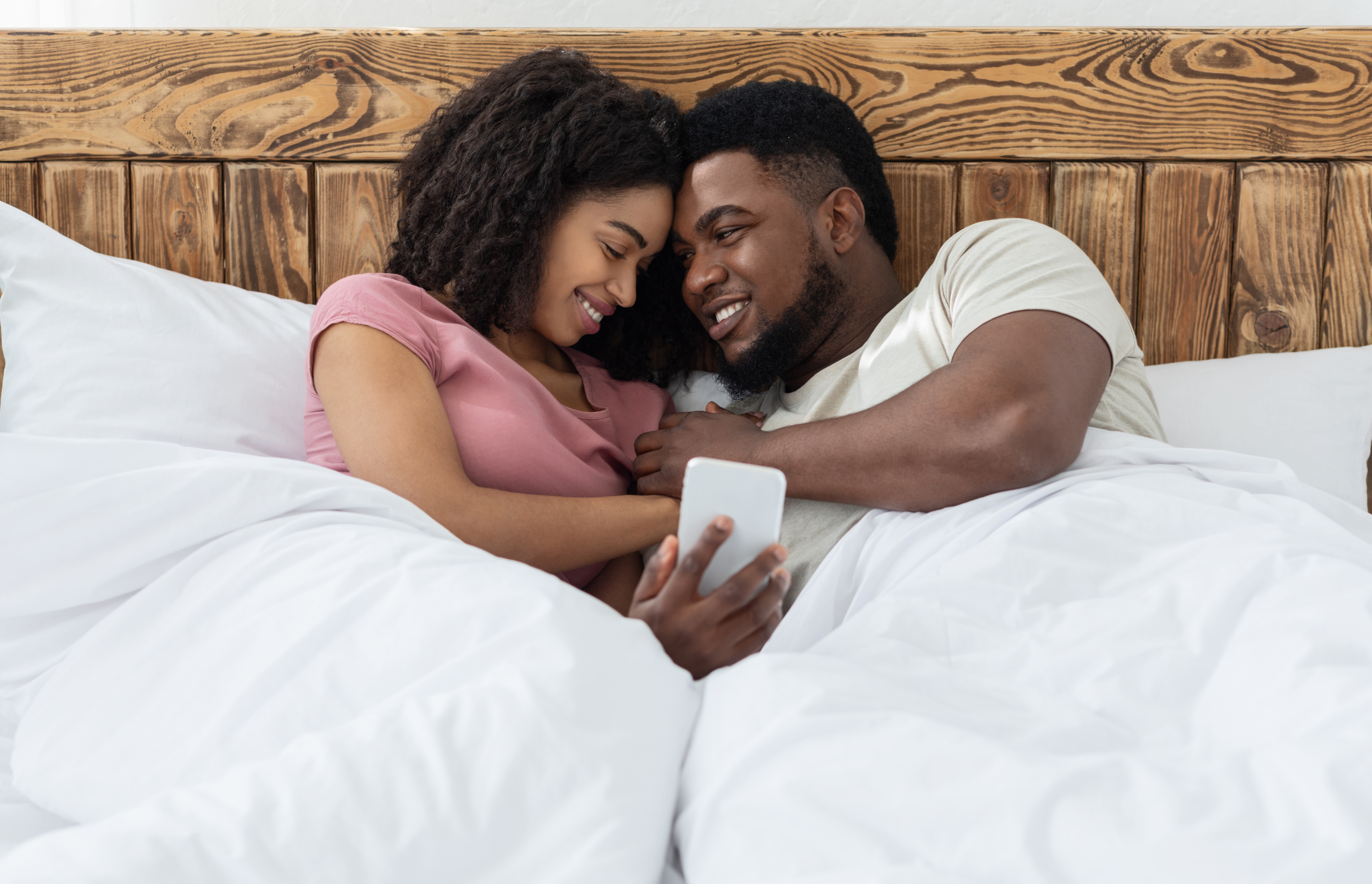 couple watching video on phone in bed